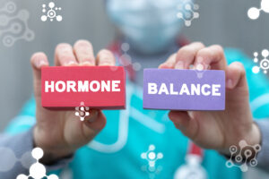 A compounding pharmacist holds up two blocks with the words "hormone" and "balance" on them, representing equal levels of the hormones.